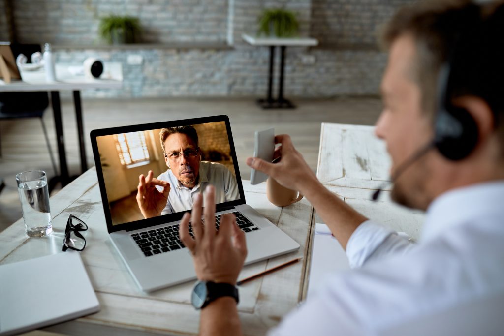 Close-up of businessman using laptop while making video call with a colleague from the office.