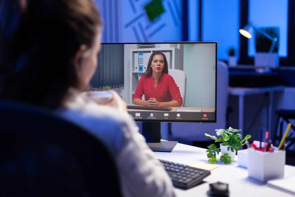 Manager talking with teamates during online teleconference at midnight from business office planning marketing strategy. Overworked freelancer using modern technology network wireless late at night